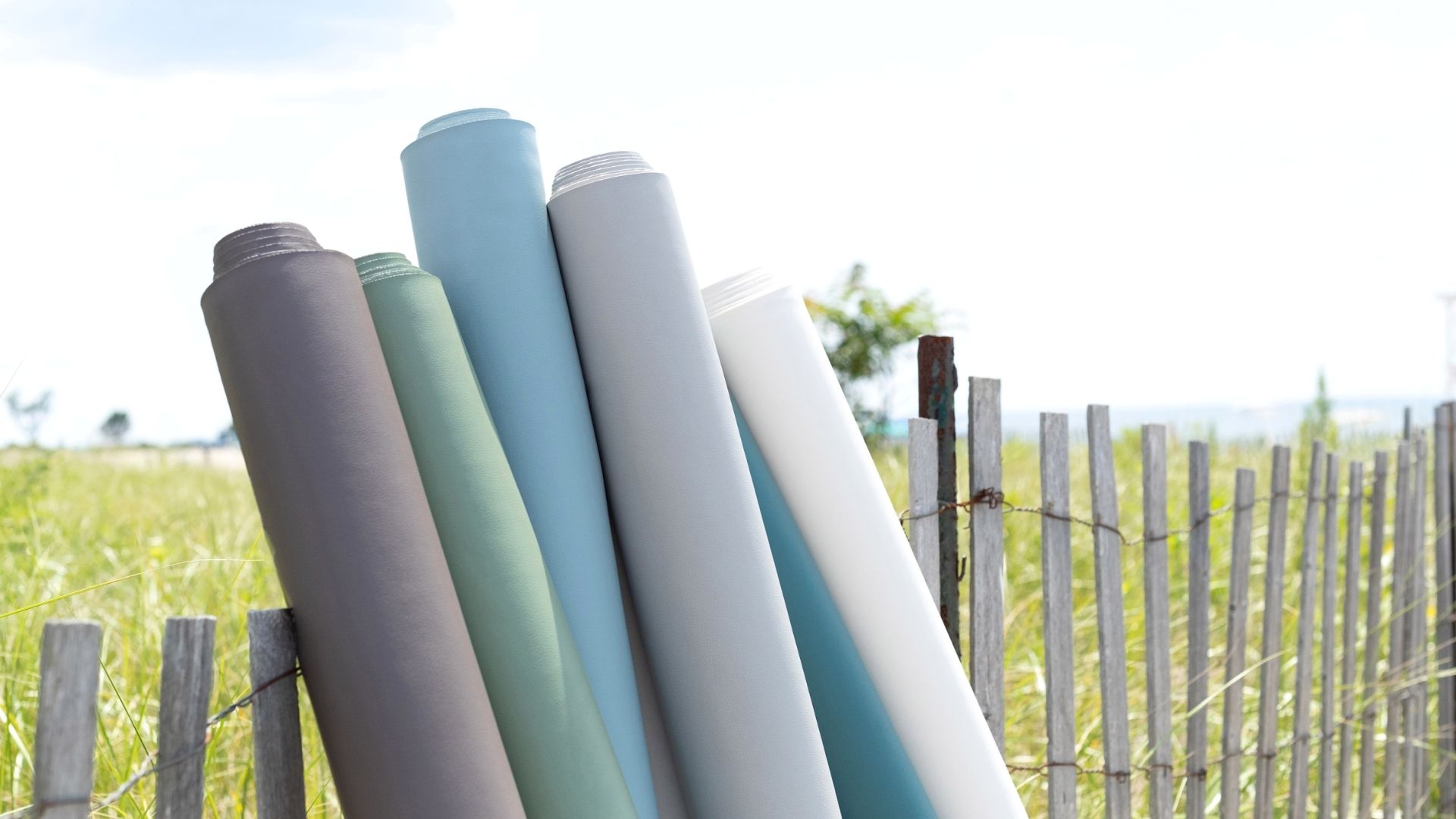 rolls of fabric outside on fence